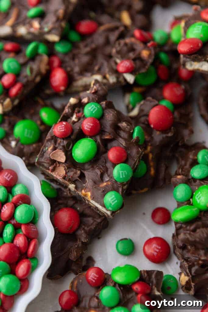Multiple pieces of Christmas peanut pretzel M&M's bark in a pan with a bowl of M&M's next to it, ready for serving