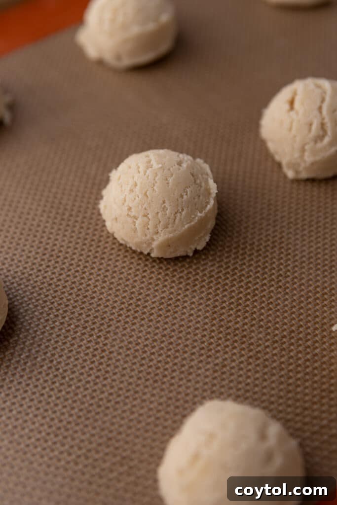 Uniformly scooped cookie dough balls arranged on a parchment-lined baking sheet