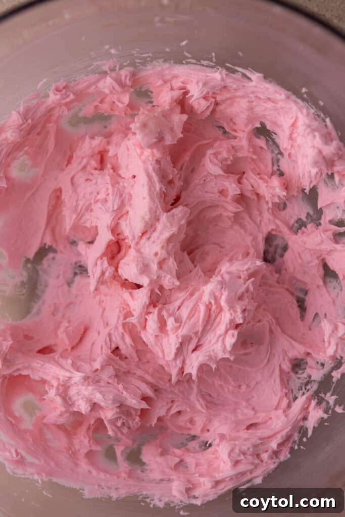 Vibrant pink buttercream frosting in a mixing bowl, ready for decorating