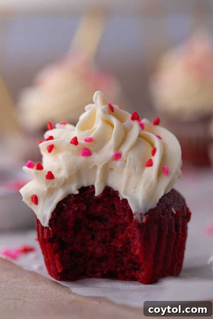 A close-up shot of a small batch red velvet cupcake, showcasing its perfectly swirled frosting and a tantalizing bite taken out.