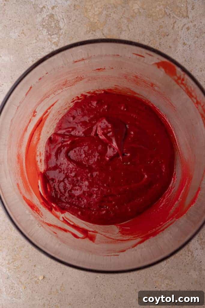 A bowl showcasing the fully mixed red velvet cupcake batter, smooth and uniformly red.