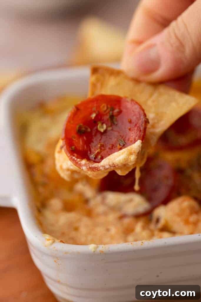 A scoop of the cottage cheese pizza bowl dip on a chip, ready to be enjoyed.