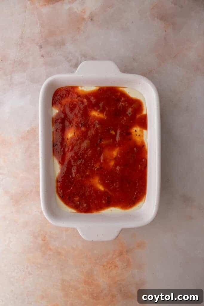 Marinara sauce being added to the cottage cheese base in a dish.