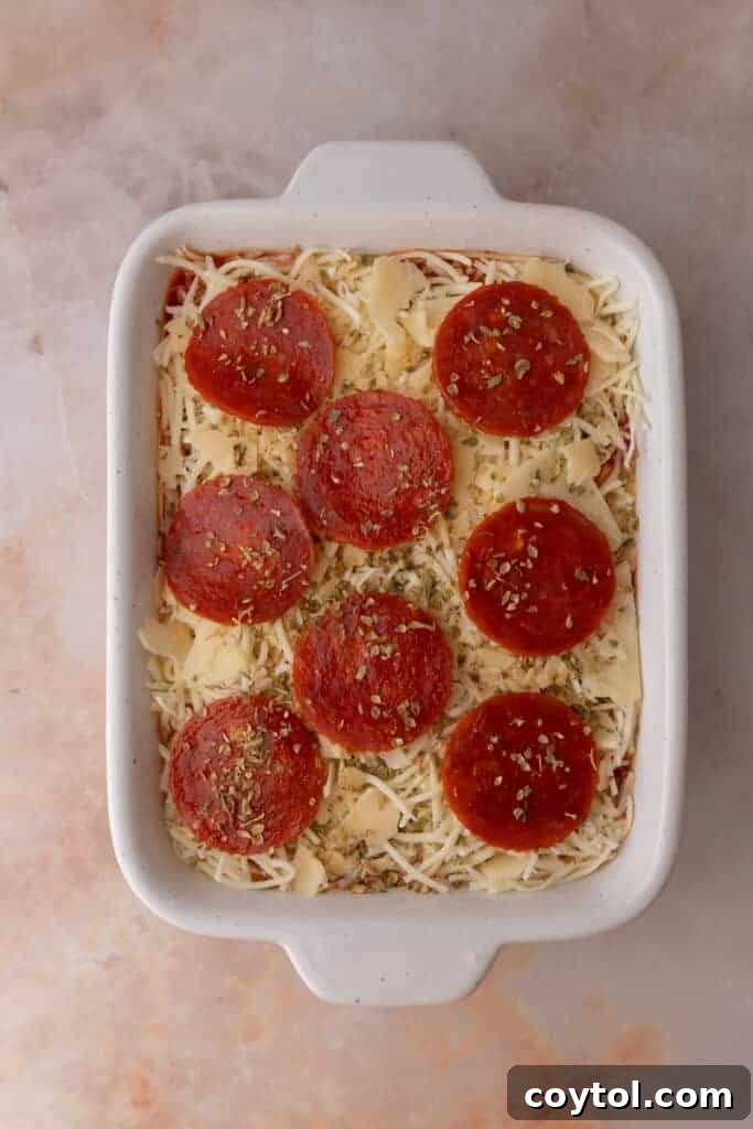 Turkey pepperoni slices topping the shredded cheese layer in the dish.