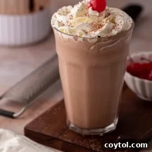 side view of the chocolate milkshake recipe with a blender behind it