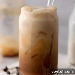 an iced hazelnut oatmilk shaken espresso starbucks drink in a glass with a straw