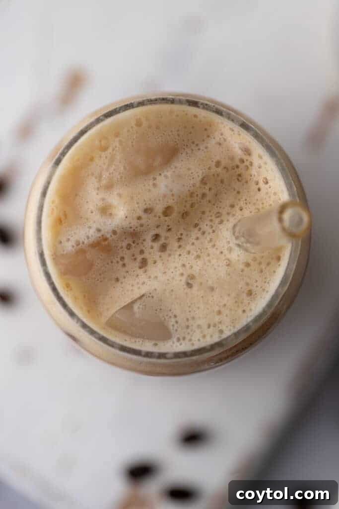 An overhead view of the ingredients and a prepared Iced Hazelnut Oatmilk Shaken Espresso Starbucks copycat drink, highlighting its beautiful layers and inviting appearance.