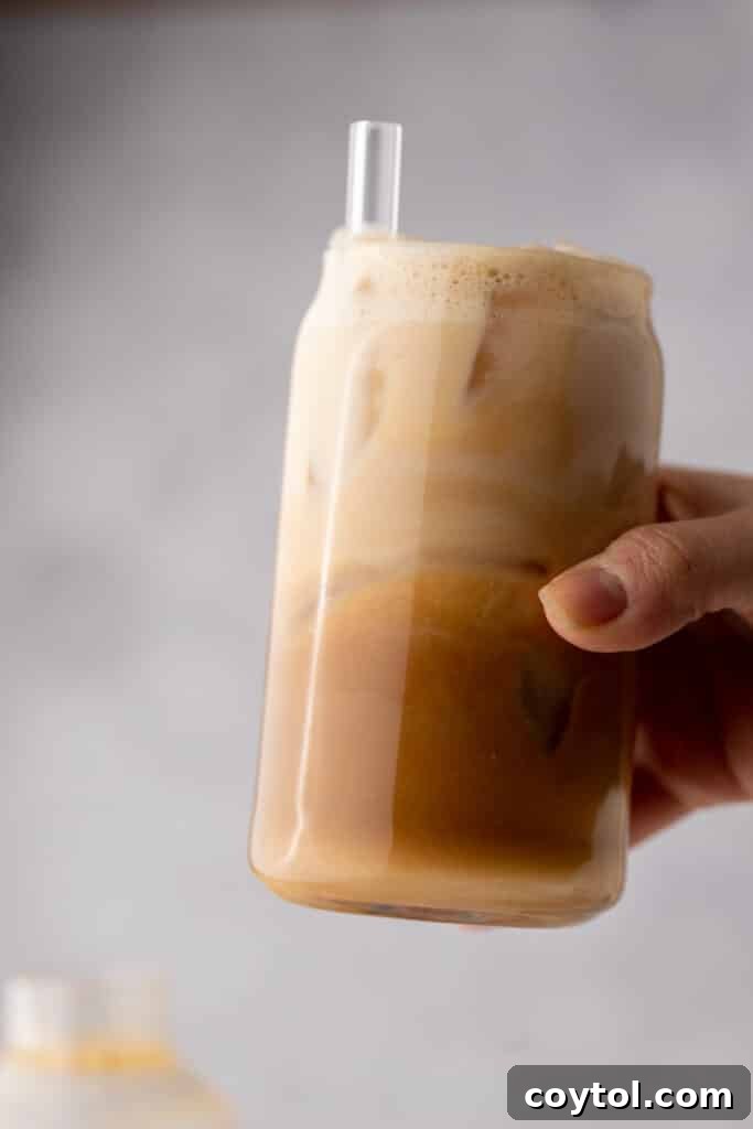 A hand holding a beautifully made Iced Hazelnut Oatmilk Shaken Espresso Starbucks copycat drink, ready to be enjoyed.