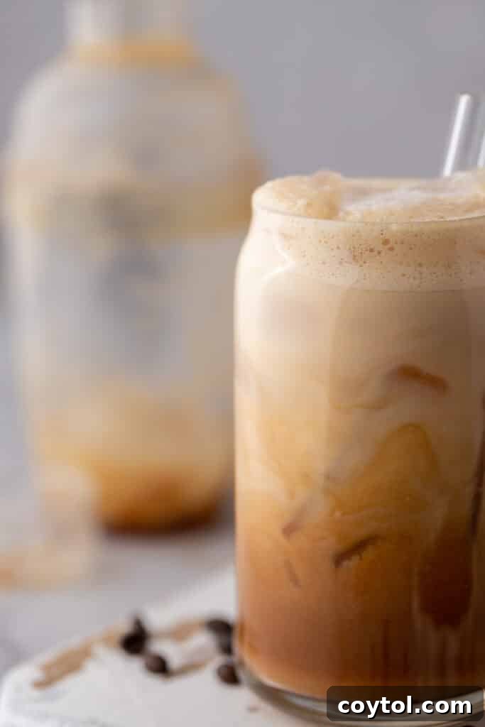 A close-up side view of an Iced Hazelnut Oatmilk Shaken Espresso, showing the beautiful layers of espresso, ice, and oat milk.