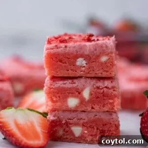 Three strawberry brownies stacked on top of each other, glistening with glaze.