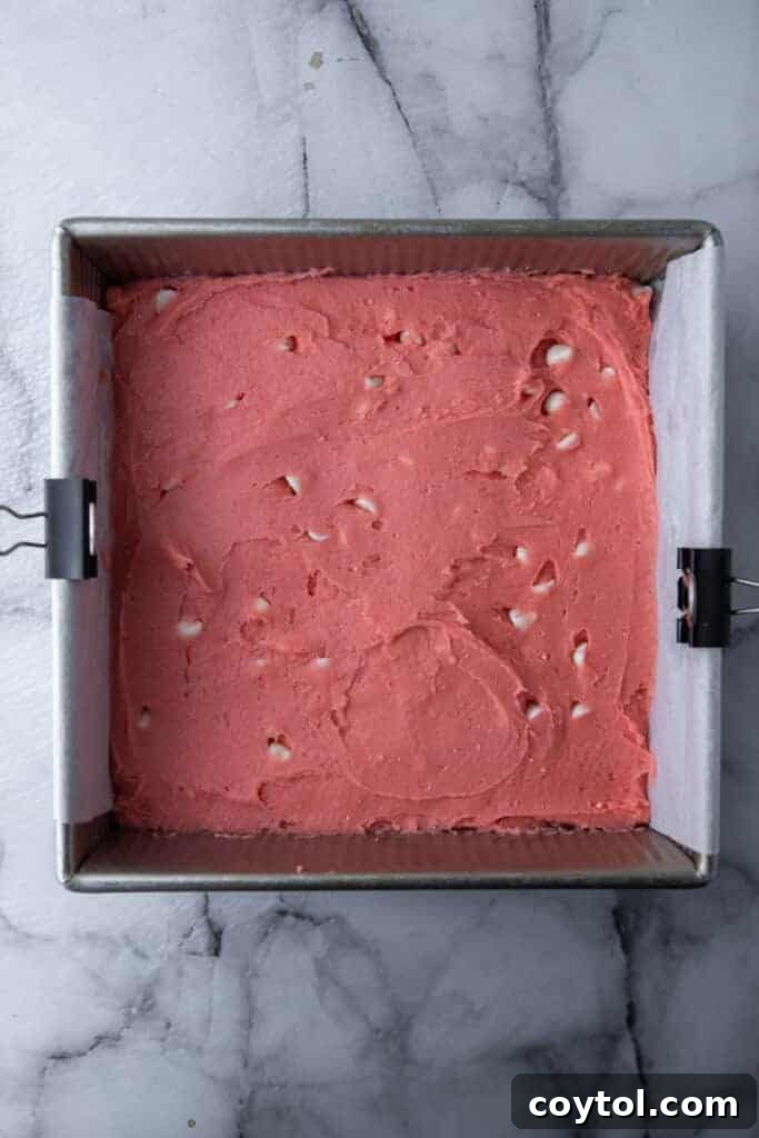 Smooth strawberry brownie batter spread evenly in a prepared baking pan, ready for the oven.