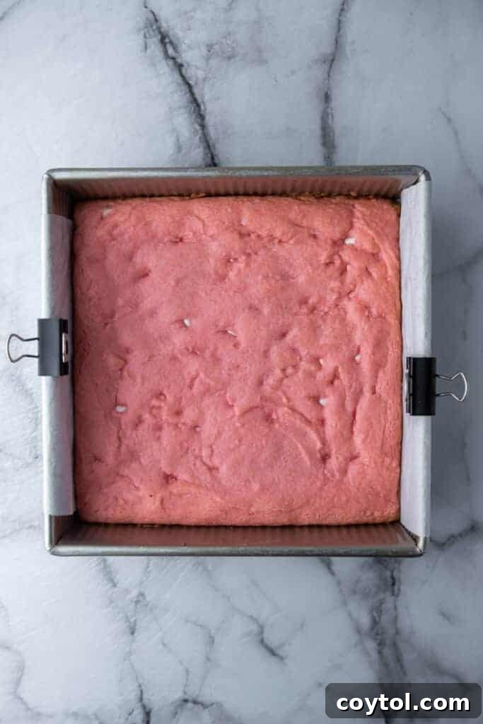 Freshly baked strawberry brownies cooling in the pan, displaying a perfect golden-pink crust.