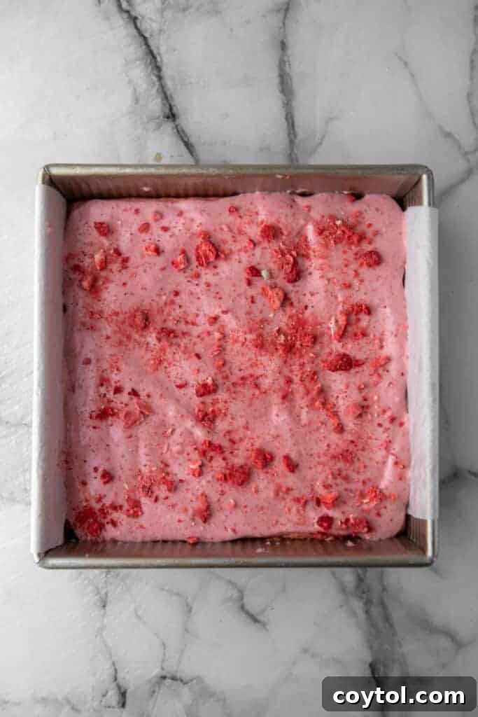 Completely cooled strawberry brownies in the pan, topped with a beautiful, set pink glaze.