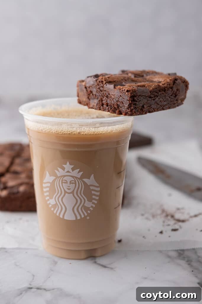 a brownie sitting on the rim of a cup of coffee