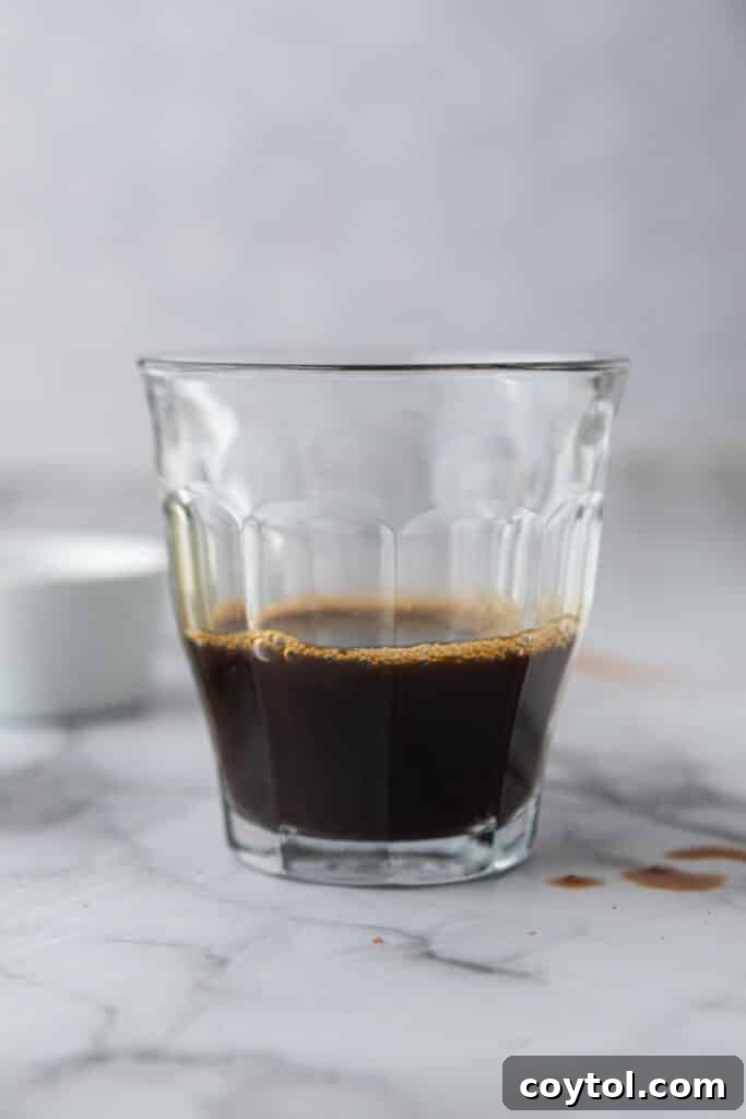 Close-up of freshly brewed espresso in a clear glass cup.