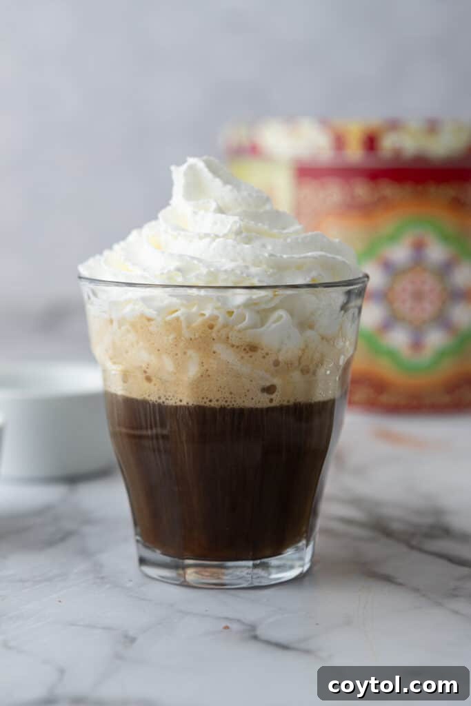 Espresso layered with a generous dollop of whipped cream in a clear glass cup.