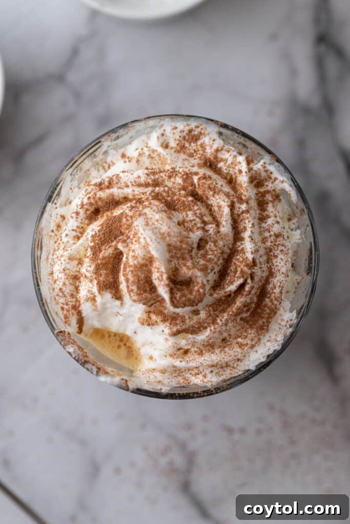 Overhead shot of espresso topped with a generous swirl of whipped cream in a glass.