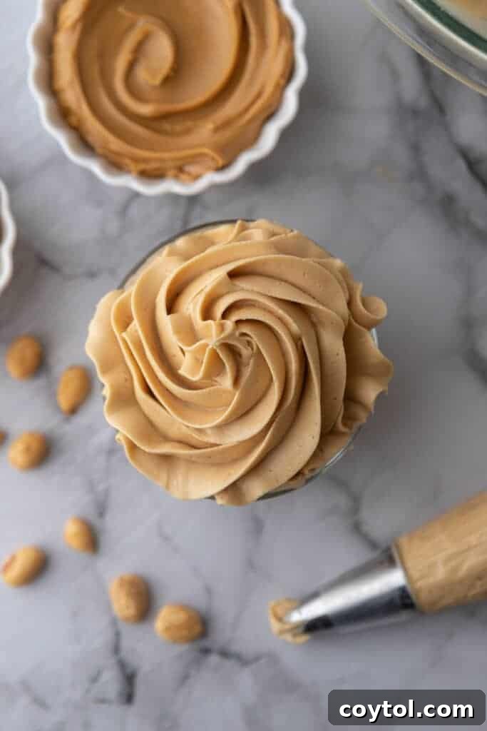 Overhead shot of creamy peanut butter icing in a small glass cup, garnished for serving.