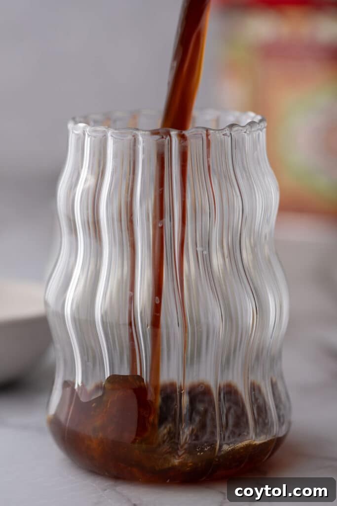 Effortless Homemade Brown Sugar Iced Coffee Indulgence 6 Hot coffee being poured over brown sugar in a glass.