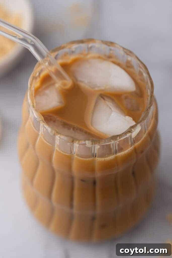 Effortless Homemade Brown Sugar Iced Coffee Indulgence 8 Angled overhead shot of a brown sugar iced coffee in a glass, with a spoon resting on the side.