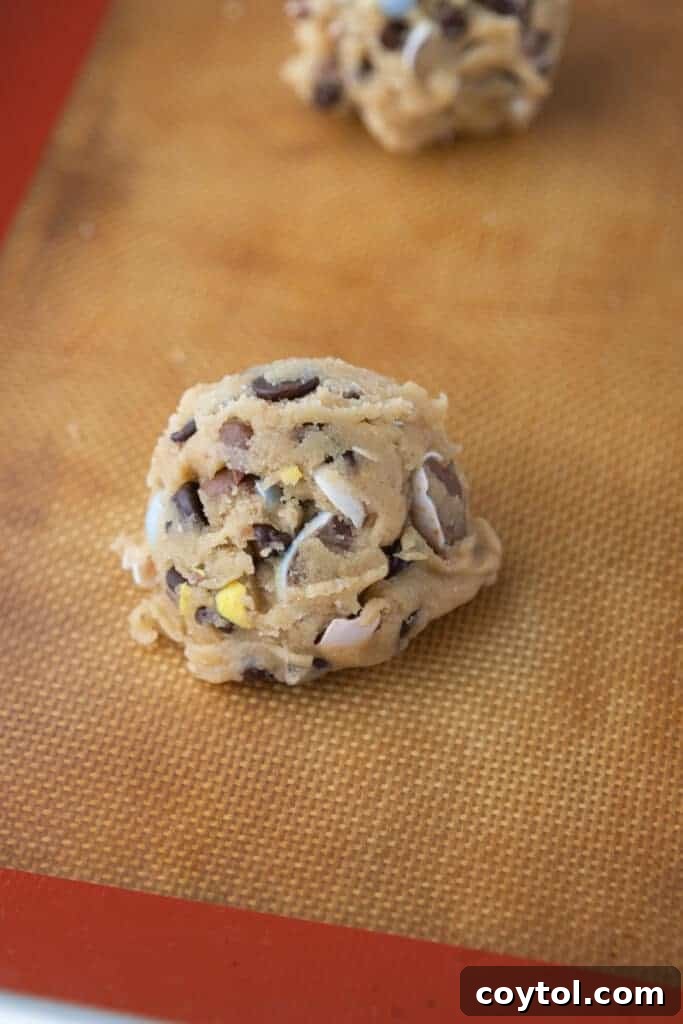 Irresistible Easter Mini Cadbury Egg Chocolate Chip Cookies 7 Raw cookie dough ball placed on a parchment-lined baking sheet