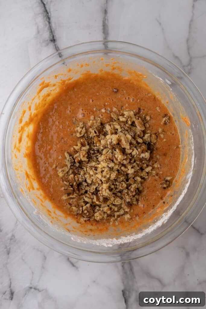 walnuts being mixed with the batter in a bowl