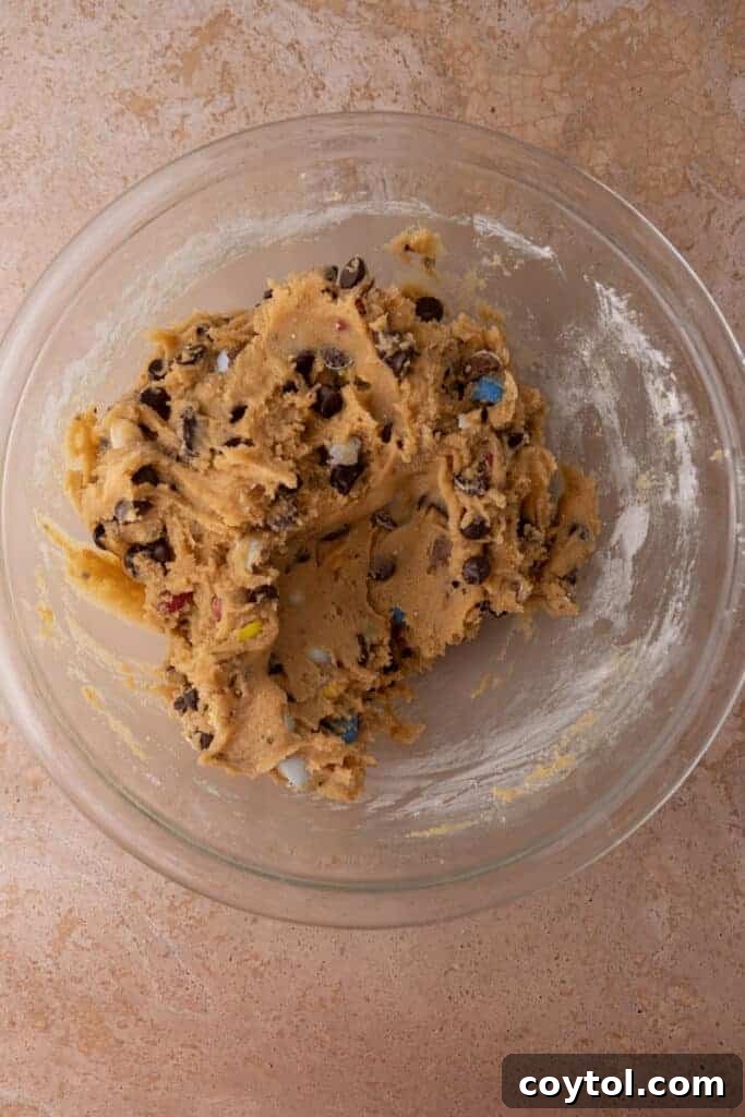 A large mixing bowl containing fully mixed cookie dough, smooth and ready to be transferred into the skillet for baking.
