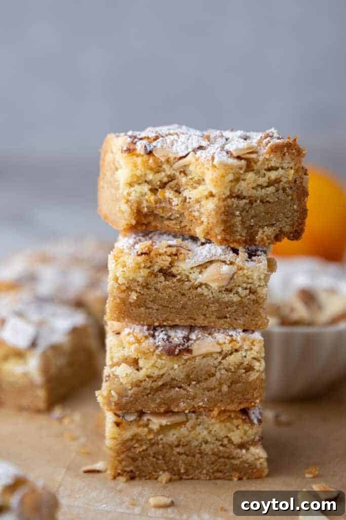 A stack of golden brown almond croissant blondies, showcasing their thickness and almond topping.