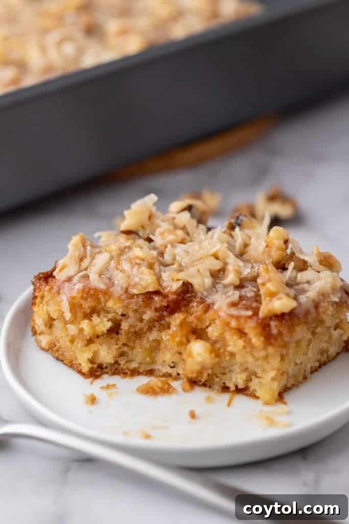 A delectable slice of moist Tornado Cake, revealing its pineapple-infused layers and rich coconut pecan topping, served elegantly on a plate.