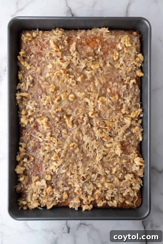 The finished Tornado Cake resting in its pan, fully covered with the set coconut pecan icing, ready to be sliced.