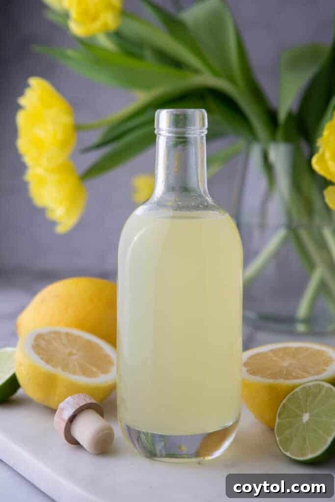 Easy Homemade Lemon Sour Mix Recipe 2 A bottle of freshly made homemade lemon sour mix on a wooden table, ready for use in cocktails.