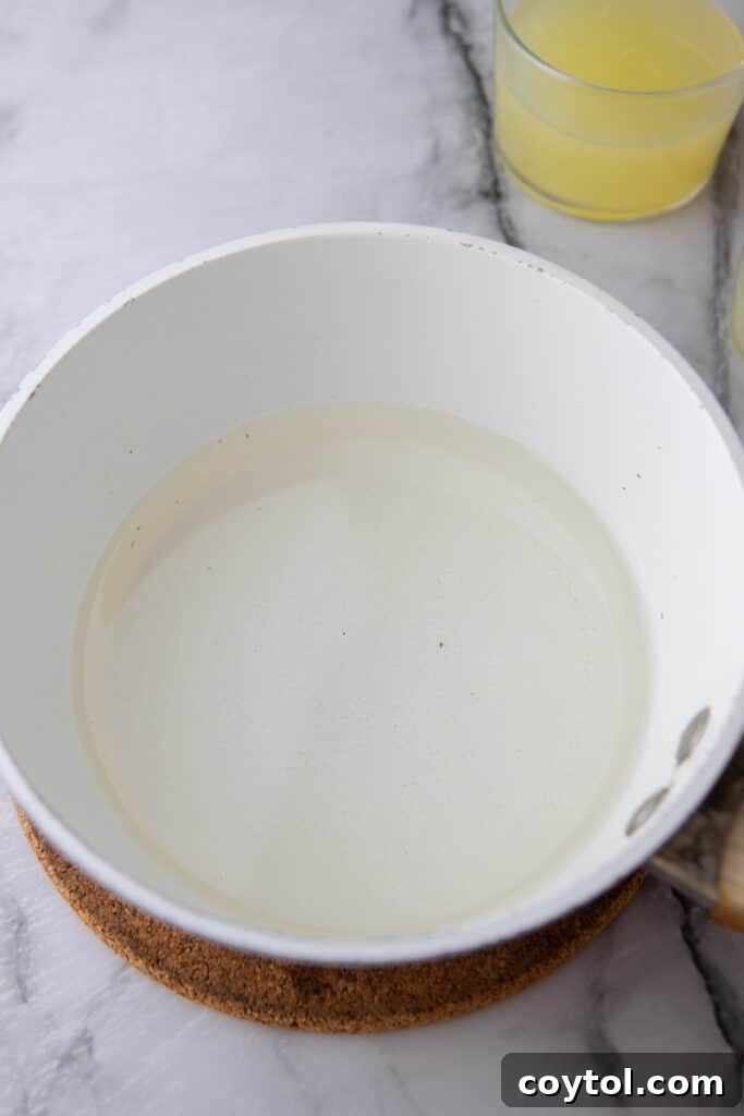 Easy Homemade Lemon Sour Mix Recipe 4 Sugar and water simmering in a small pot to create simple syrup.