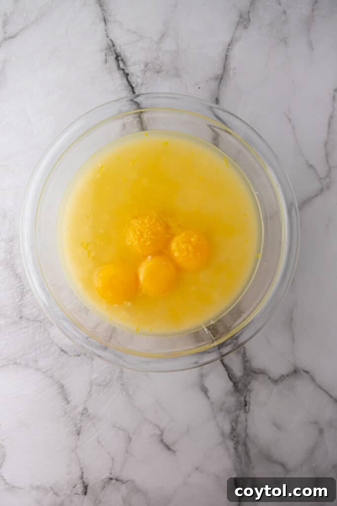 Raw ingredients for the lemon pie filling, including egg yolks and condensed milk, in a mixing bowl before combining.