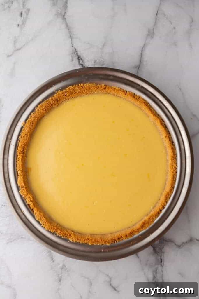 The fully baked lemon pie, showing a set, slightly golden filling in the graham cracker crust.