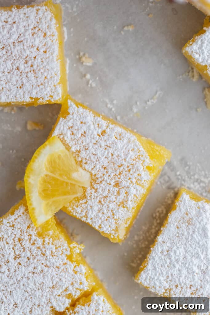 An overhead shot of a pan of freshly baked and sliced lemon bars, beautifully dusted with powdered sugar.
