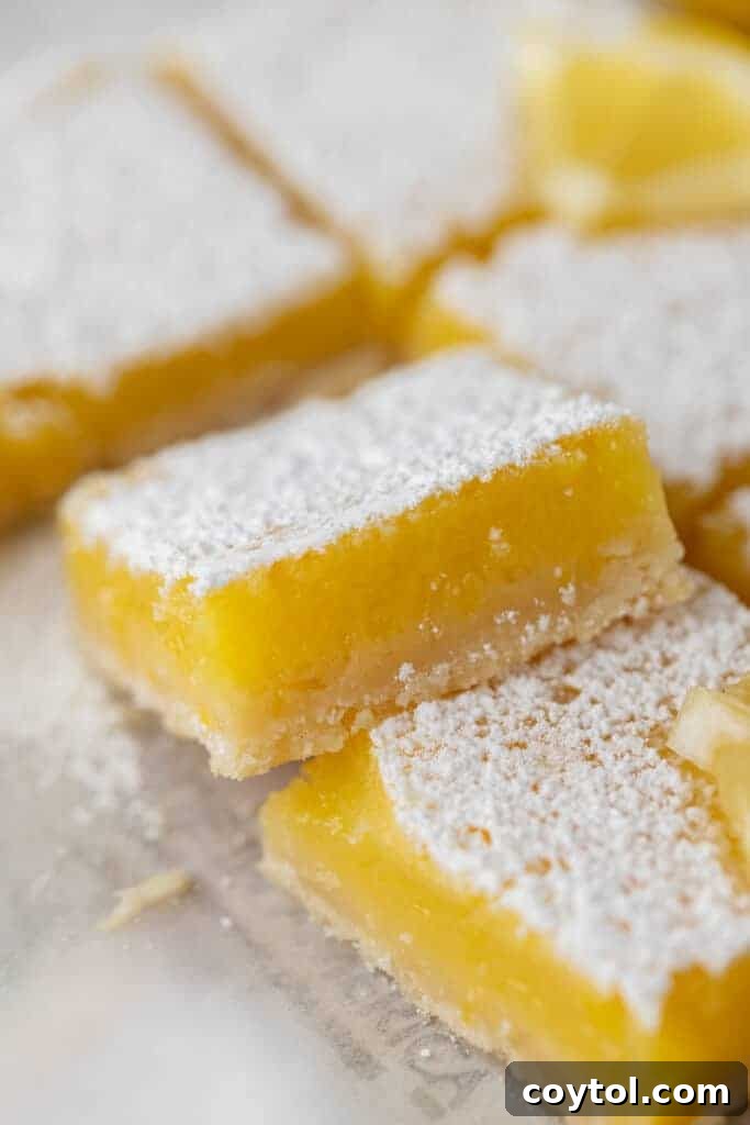 A single square of the easy lemon bar recipe, dusted with powdered sugar, showcasing its thick lemon layer and buttery shortbread base.