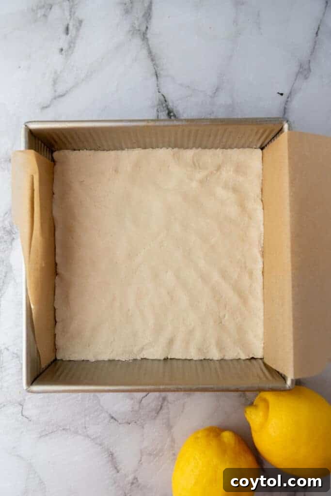 Shortbread crust mixture pressed evenly into a parchment-lined baking pan.