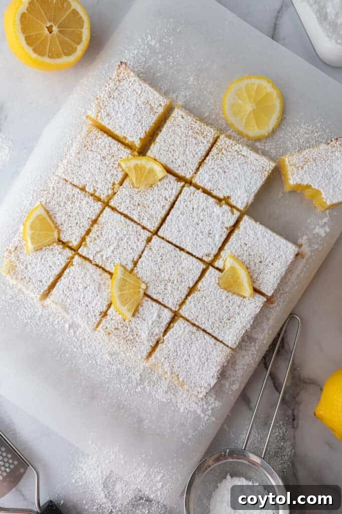 Baked lemon bars, beautifully golden, cut into perfect squares in the pan, ready for dusting.