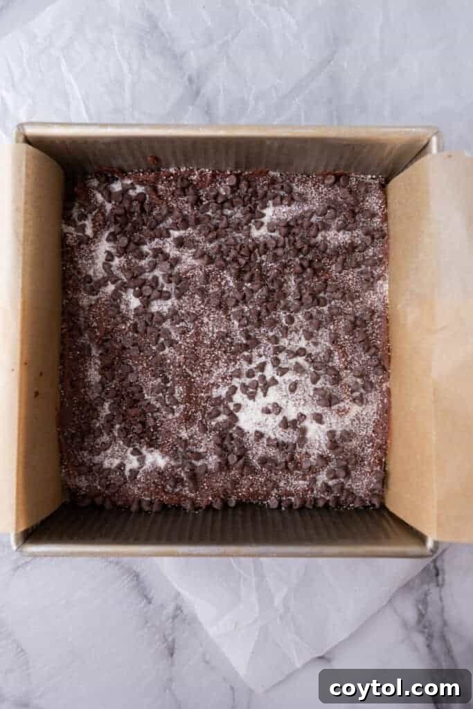 chocolate sugar cookie dough pressed into a parchment-lined baking pan, ready for baking