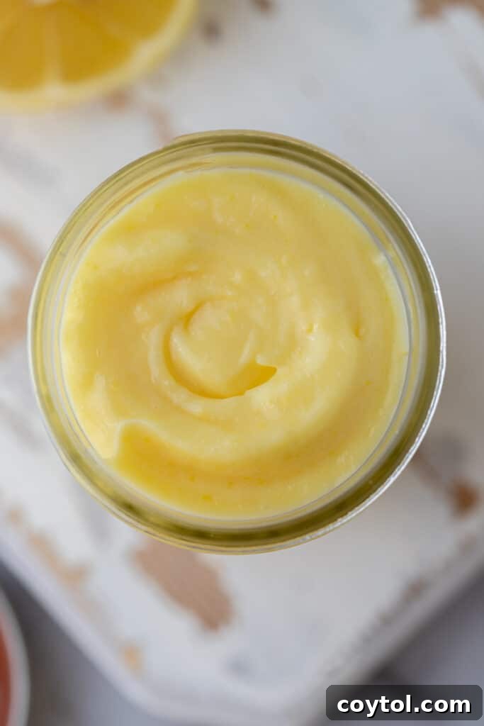 Microwave Lemon Curd: Zesty Perfection in Minutes 11 Overhead shot of microwave lemon curd in a glass jar, garnished with a fresh lemon slice.