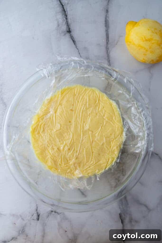 Microwave Lemon Curd: Zesty Perfection in Minutes 9 A jar of lemon curd covered with plastic wrap, cooling before chilling.