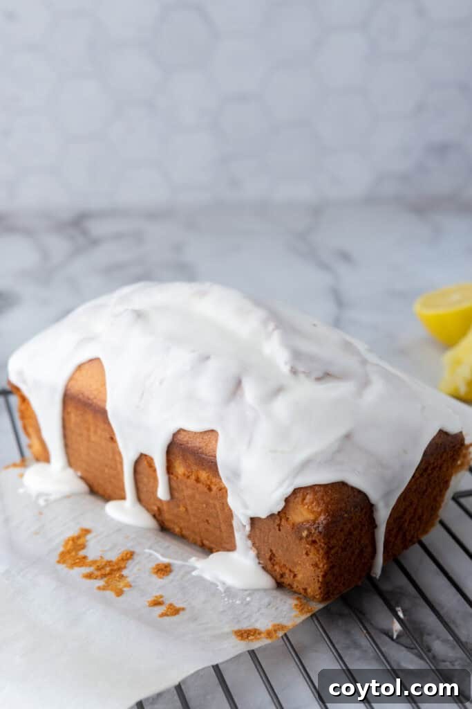 Lemon glaze being drizzled over the cooled loaf cake