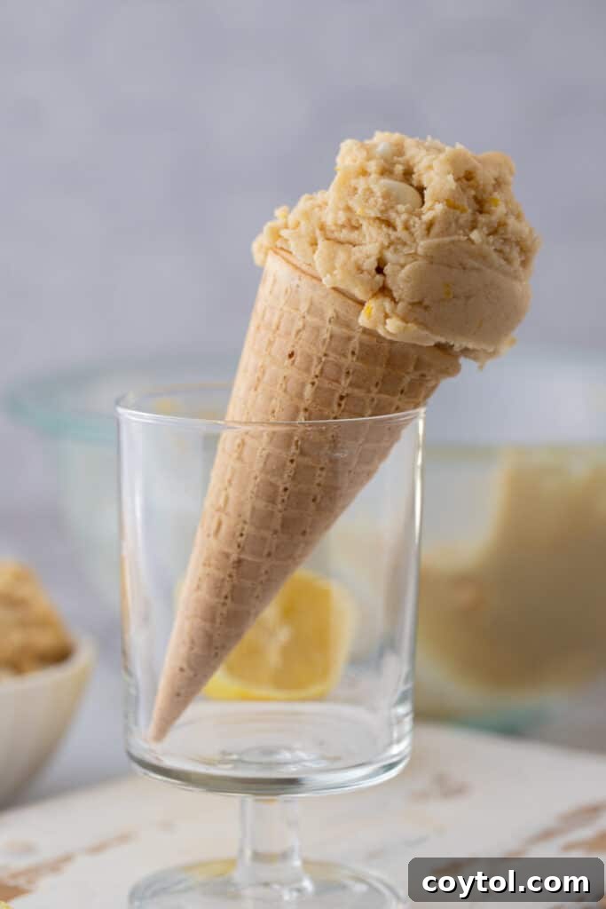 Edible lemon cookie dough artfully arranged in a waffle cone, garnished with lemon zest