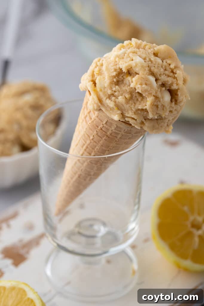 Edible lemon cookie dough shaped into a scoop and served in a waffle cone, ready to be enjoyed