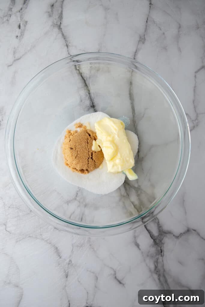 Bowl with unmixed wet ingredients for cookie dough: softened butter, granulated sugar, and brown sugar