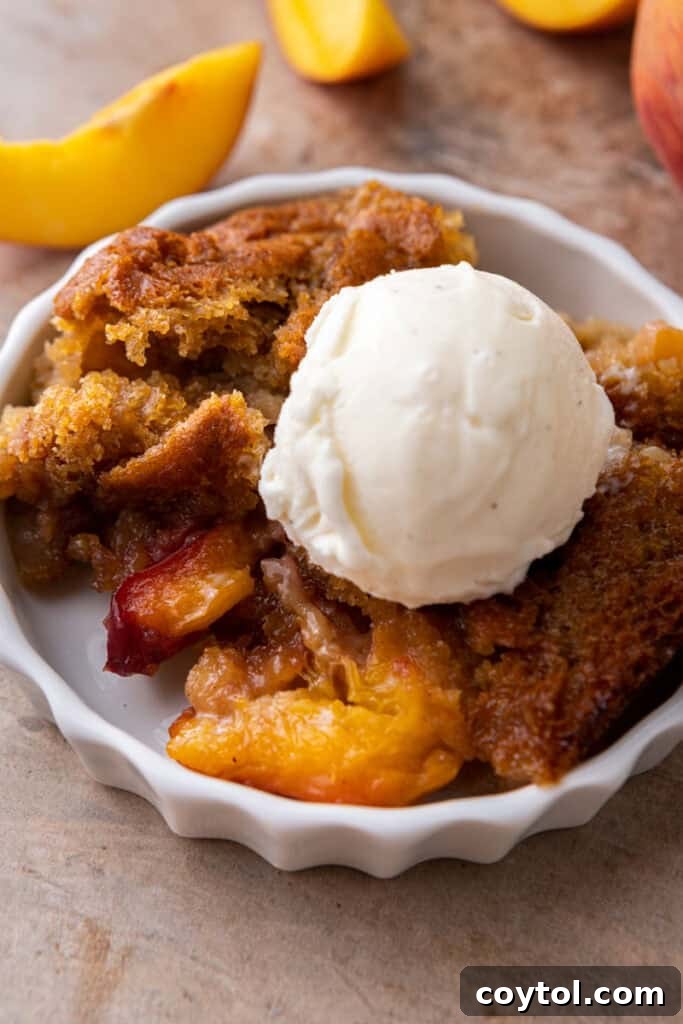 Old fashioned peach cobbler served warm on a plate with vanilla ice cream