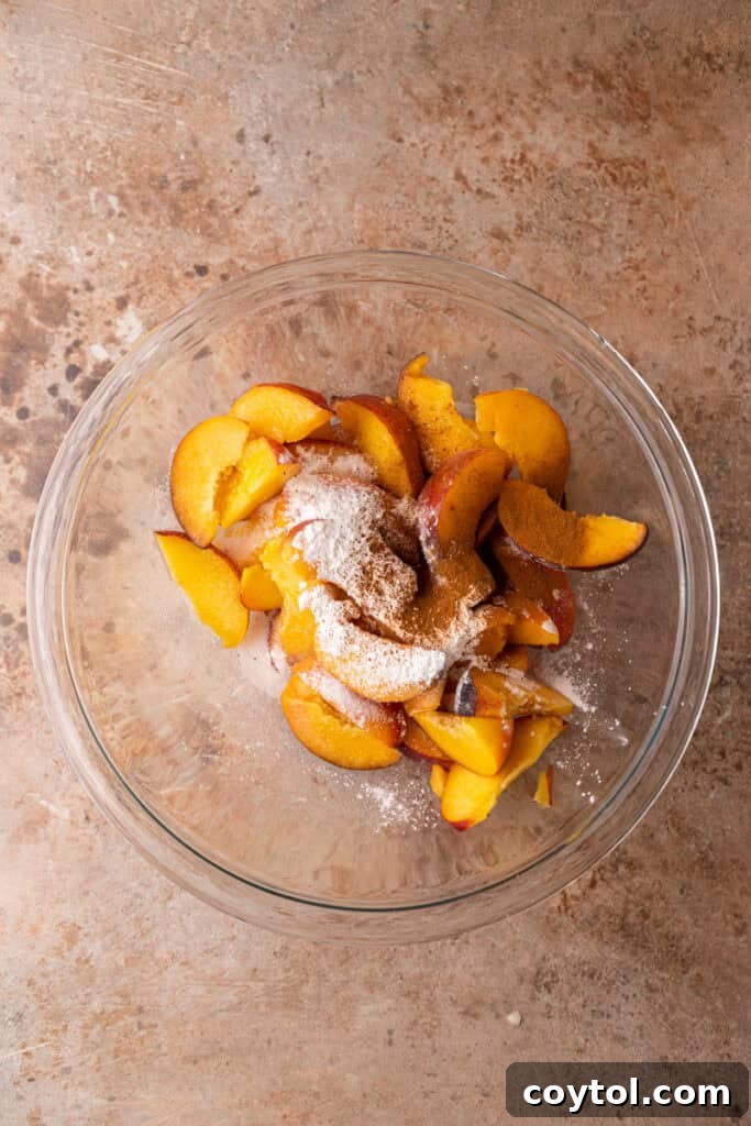 Sliced peaches mixed with sugar and spices in a bowl