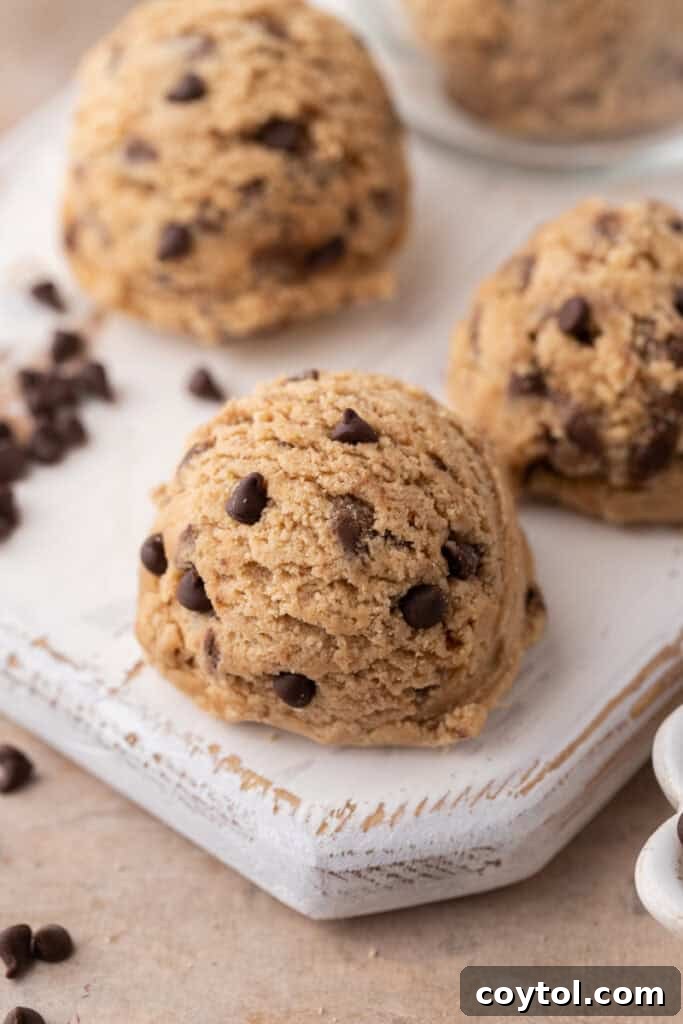 Irresistible Edible Chocolate Chip Cookie Dough 11 A small mound of brown butter edible chocolate chip cookie dough rests on a rustic wooden board, ready for a taste test or serving.