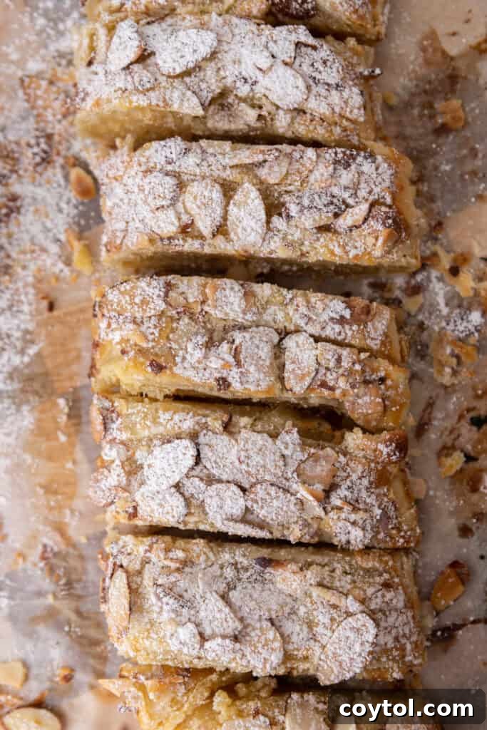 Overhead shot of a beautifully braided almond croissant danish, golden-brown and glistening with almonds.