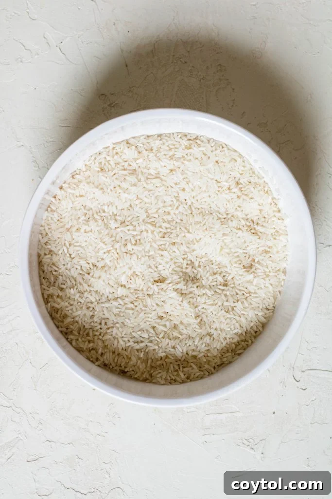 Long-grain white rice being rinsed under running water, a crucial first step for perfectly cooked stovetop rice.